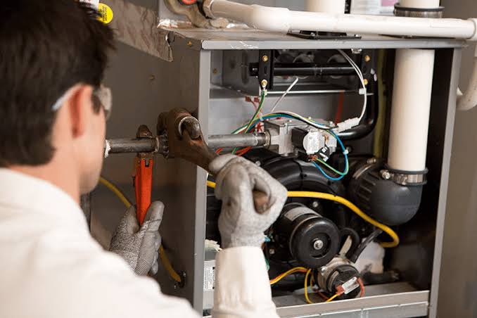 HVAC technician repairing internal components of a residential furnace