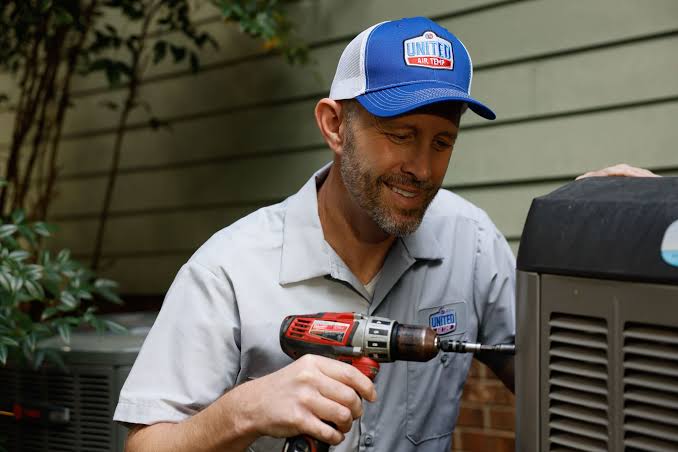 HVAC technician using a power tool on an outdoor air conditioning unit