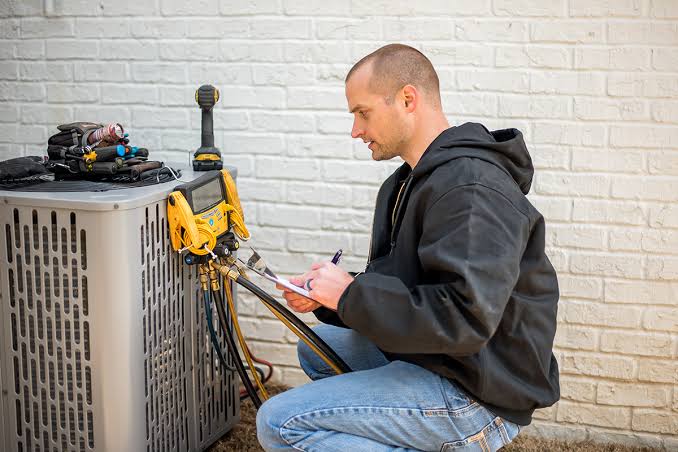 HVAC technician recording measurements beside a residential condenser