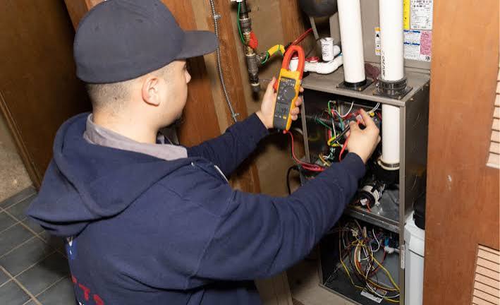 HVAC technician testing electrical components inside residential heating equipment