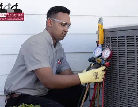 Air conditioning technician connecting pressure gauges to an outdoor unit